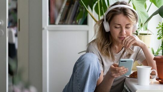 en kvinna som lyssnar på mobilen med sina hörlurar